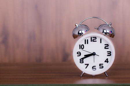 white alarm clock on wooden old backgroundの写真素材