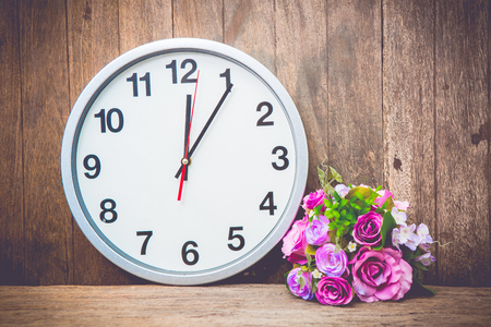 beautiful pink flower , clock on wooden background.