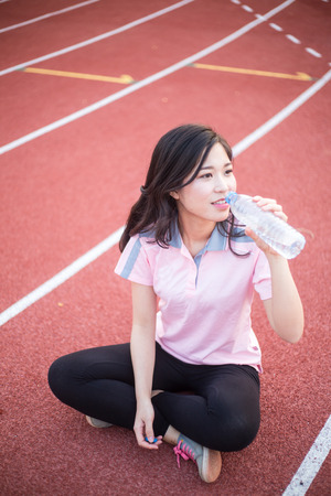 Sports beautiful woman on stadium drinking waterの写真素材