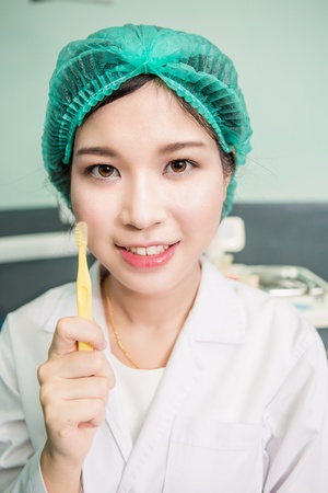 Woman dentist showing toothbrush dental care clinicの写真素材