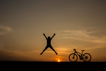 silhouette of man and bicycle on sunset skyの写真素材