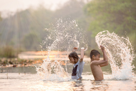 asian boy and girl playing in the riverの写真素材