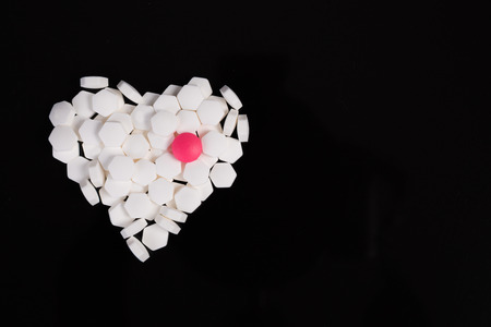white drug  heart shape on  black backgroundの写真素材