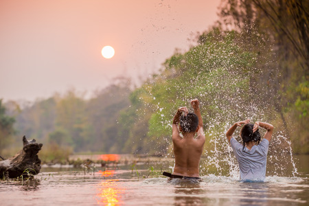 asian boy and girl playing in the riverの写真素材