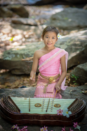 Thai girl in Thai dress playing Thai music inthe parkの写真素材