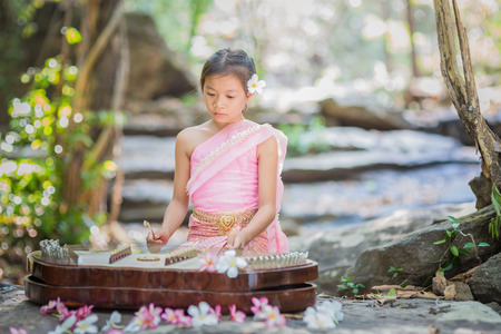 Thai girl in Thai dress playing Thai music inthe parkの写真素材