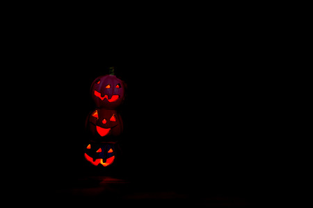 Scary Halloween pumpkins  on black background. Scary glowing faces trick or treatの写真素材