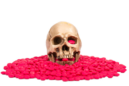 skull hold drug's red pill in the mount with white backgroundの写真素材