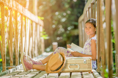 asian girl reading book on the old bridge in the forestの写真素材