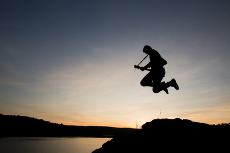 Silhouette man jumping with guitar in the sunset or sunrisrの写真素材