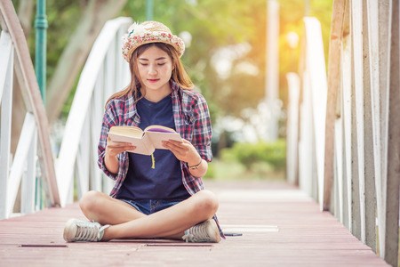 young woman reading book on bridgeの写真素材