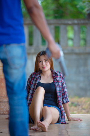 Violence against women: Man threatening beaten up girl with gunの写真素材