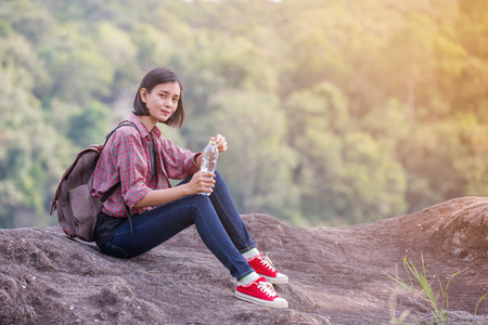 Woman tourist with backpack drinking water in natureの写真素材