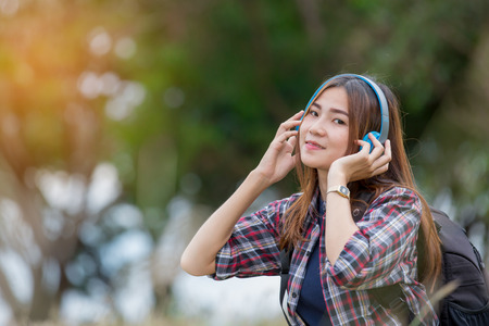 portrait of young  asian woman listening music on green grassの写真素材