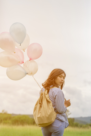 Happy asin beautiful woman with colorful balloons in the grass fieldの写真素材
