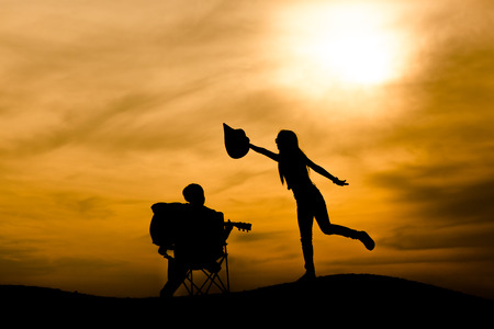silhouette of musician with guitar at sunsetの写真素材