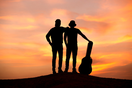 silhouette of musician with guitar at sunsetの写真素材
