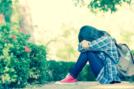 sad young woman sitting in the parkの写真素材