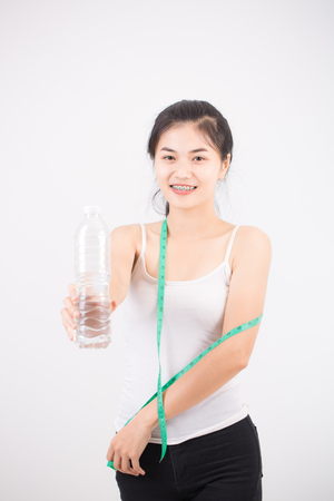 sport and heath concept - beautiful sporty woman drinking water with measuring tapeの写真素材