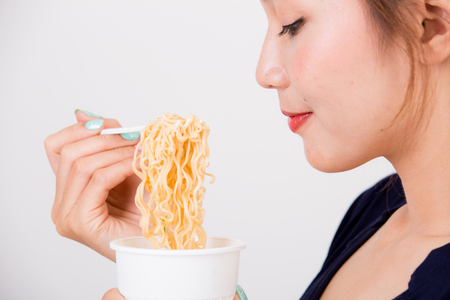 Young beautiful asian girl eating instant noodle using plastic fork.の写真素材