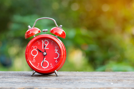 red alarm clock with coins on green background