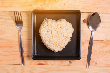 brown rice heart shape on black plate on wooden backgroundの写真素材