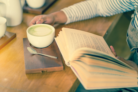 woman reading book and drinking coffeeの写真素材