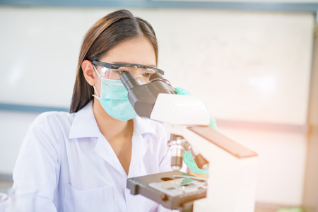 Doctor woman or chemist working with  microscope in laboratory roomの写真素材