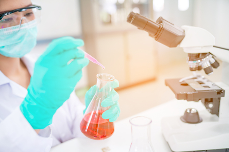 Doctor woman or chemist use dropper drop liquid chemical in to test tube in laboratory roomの写真素材