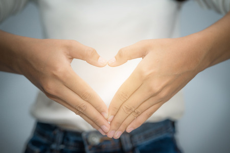 woman hand making  heart shape with her fingers in front of her chestの写真素材