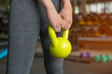 Closeup of  woman holding a dumbbell in gymの写真素材