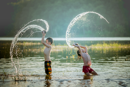 asian children playing splashing water in the river.の写真素材
