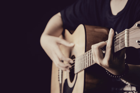 close up of woman hands playing guitar in the dark background,vintage styleの写真素材