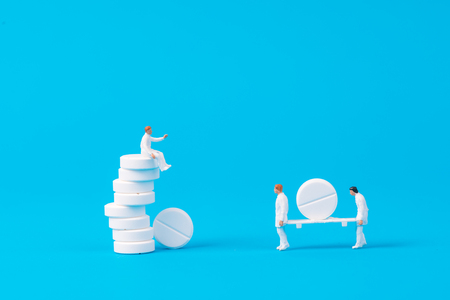 miniature people with white medical drug on blue background,health conceptの写真素材