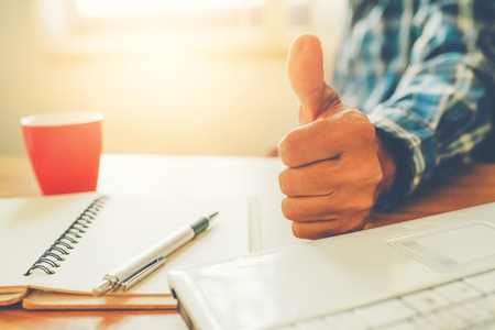 htumb up with laptop and coffee cup on tableの写真素材