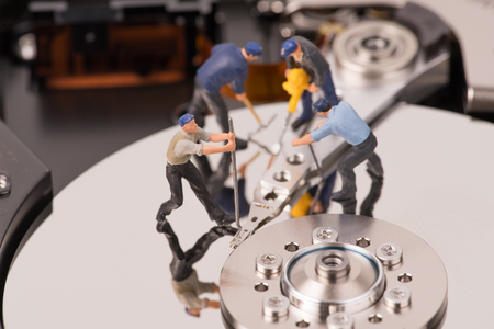 technicial team miniature people repairing  hard drive. Figures of people. The team of employeesの写真素材