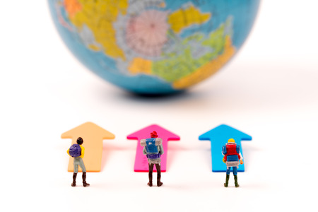 Miniature figure person backpack , travelers  standing on arrow with world map background,tourism conceptの写真素材