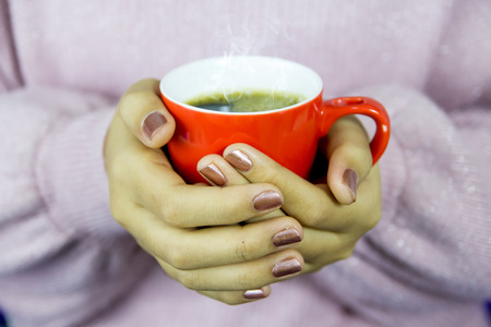 close up woman hands holding red cup of coffee