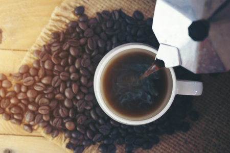 White cup of coffee with coffee bean on sackcloth backgroundの写真素材