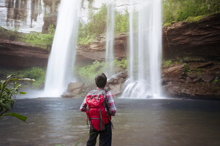backpacker standing infront of waterfallの写真素材