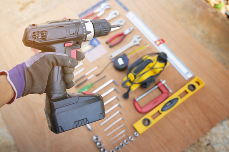 Hand holding drill with craftsman tool background