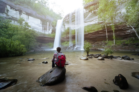 Backpacker sitting in front of waterfallのeditorial素材