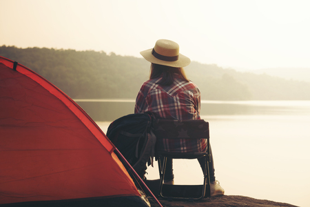 Backpack woman sitting beside the river with sunset backgroundの写真素材