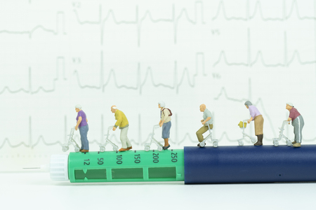Miniature ederly group walking on insulin pen with cardiogram,medical conceptの写真素材