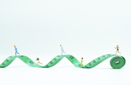 Miniature people running on measure tape. healthy concept