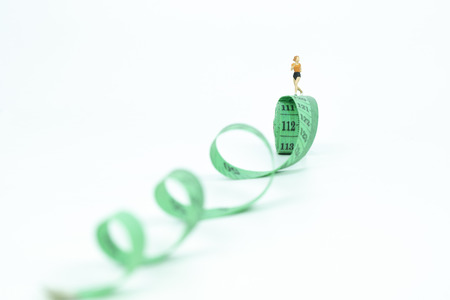 Miniature people running on measure tape. healthy concept