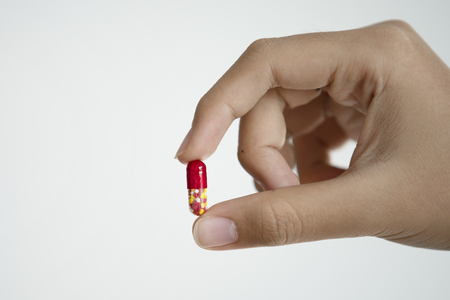 Hand holding medical drug capsule on white backgroundの写真素材