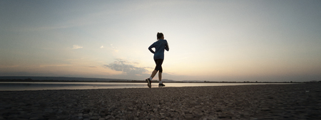 Woman running with sunset or sunrise backgroundの写真素材