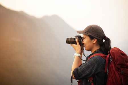 Backpacker woman take photo on peak mountainの写真素材