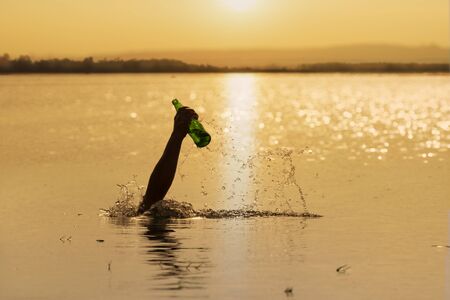 hand holding glass bottle garbage from water,environment concept